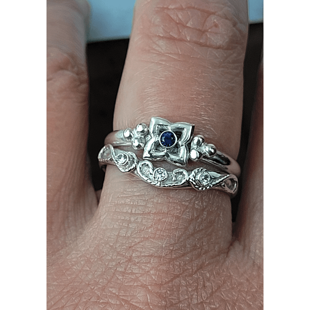 Art Deco-inspired Blue Sapphire Engagement Ring and Edwardian-inspired Scrollwork White Sapphire Curved Wedding Band in Sterling Silver on model