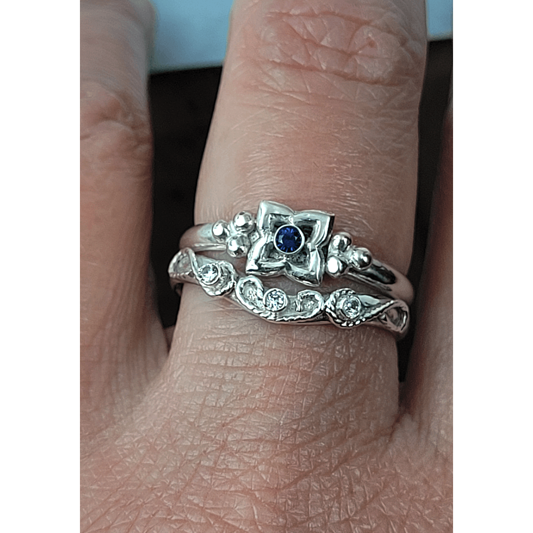 Art Deco-inspired Blue Sapphire Engagement Ring and Edwardian-inspired Scrollwork White Sapphire Curved Wedding Band in Sterling Silver on model
