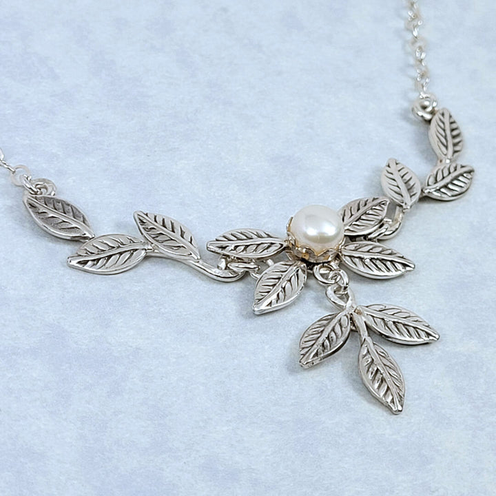 Close-up of handmade sterling silver leaves surrounding a freshwater pearl necklace
