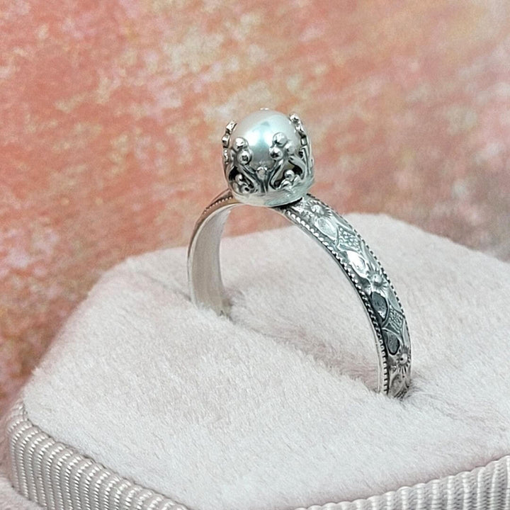 Edwardian inspired vintage style petite pearl engagement ring in sterling silver showing detail of heart-crown setting and textured band