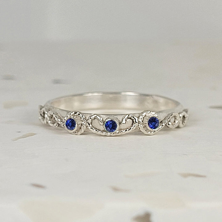 vintage-inspired scrollwork ring band with blue sapphires in sterling silver