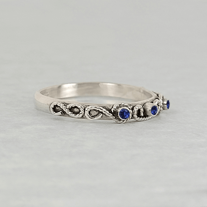 vintage-inspired scrollwork ring band with blue sapphires in sterling silver