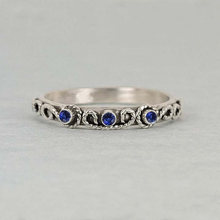 vintage-inspired scrollwork ring band with blue sapphires in sterling silver
