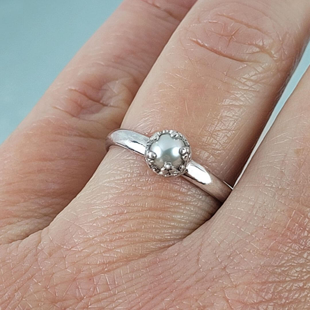 close-up of vintage style solitaire pearl engagement ring in sterling silver on hand