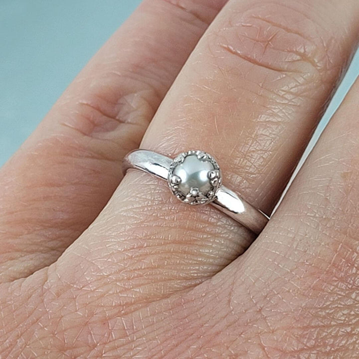 close-up of vintage style solitaire pearl engagement ring in sterling silver on hand