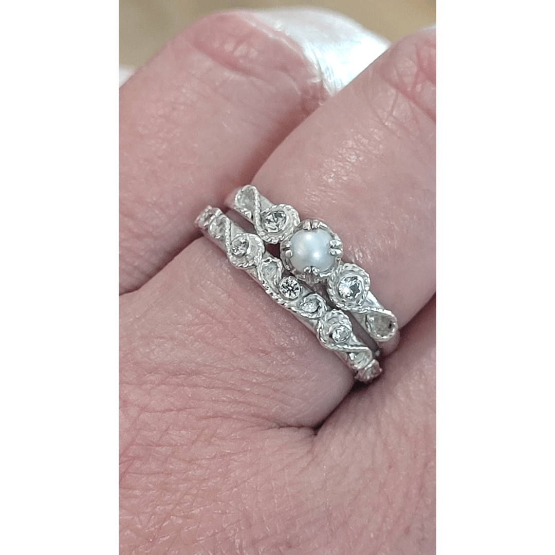 vintage style scrollwork pearl and white sapphire engagement ring and matching scrollwork white sapphire wedding band bridal ring set in sterling silver detail shot on model