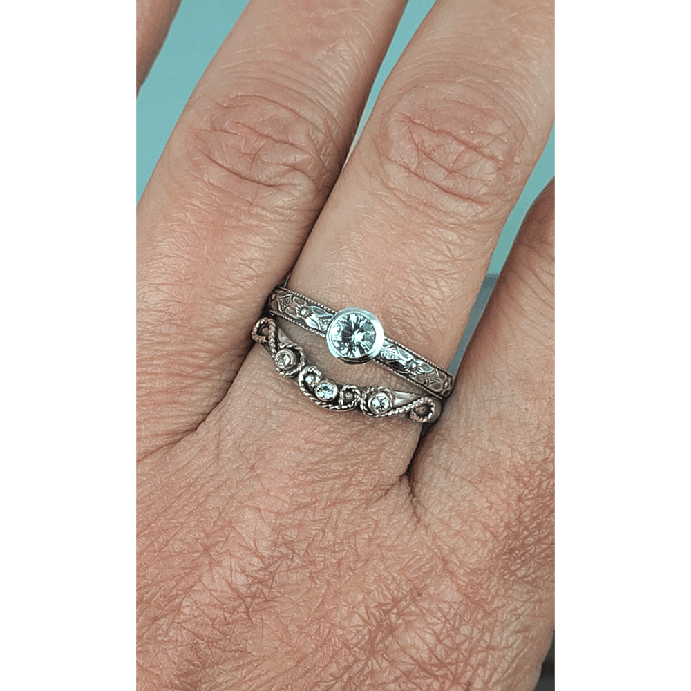 Vintage style white sapphire engagement ring and white sapphire scrollwork curved wedding band set in sterling silver on model