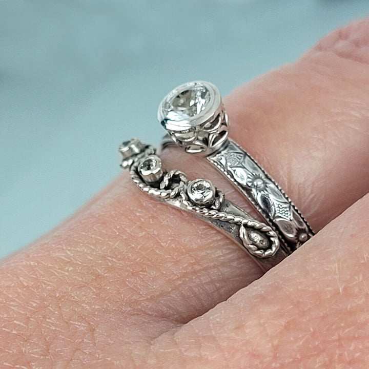 Vintage style white sapphire engagement ring and white sapphire scrollwork curved wedding band set in sterling silver on hand