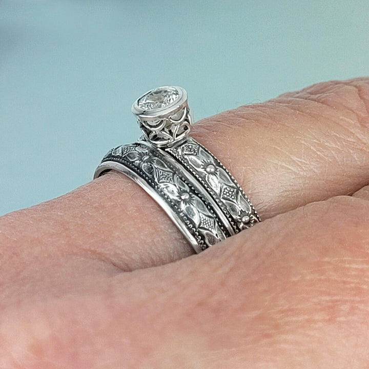 Vintage style white sapphire engagement ring and matching wedding band in sterling silver on hand