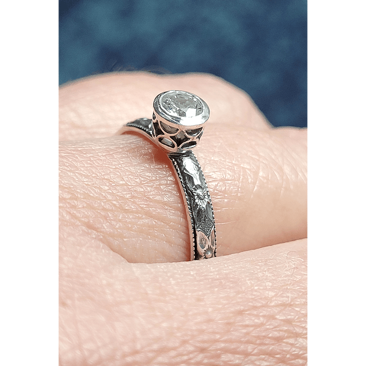 Vintage style white sapphire engagement ring with pierced bezel setting in sterling silver