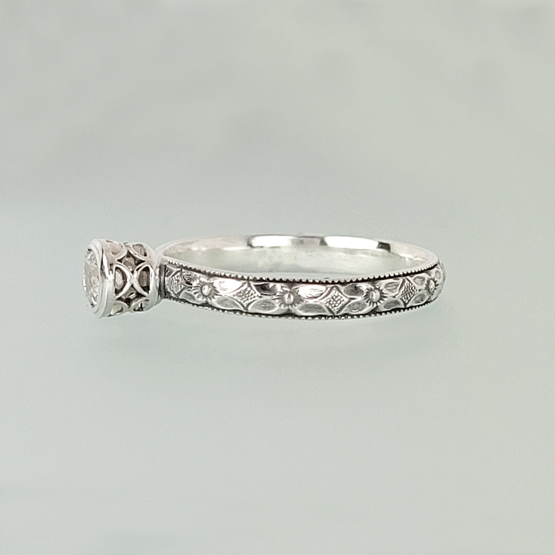 Vintage style white sapphire engagement ring with pierced bezel setting in sterling silver side view