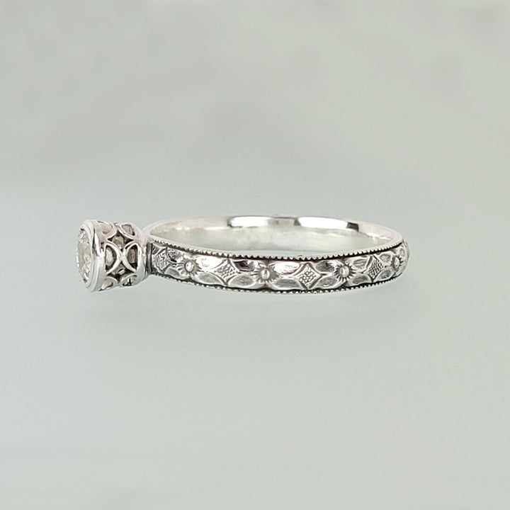 Vintage style white sapphire engagement ring with pierced bezel setting in sterling silver side view