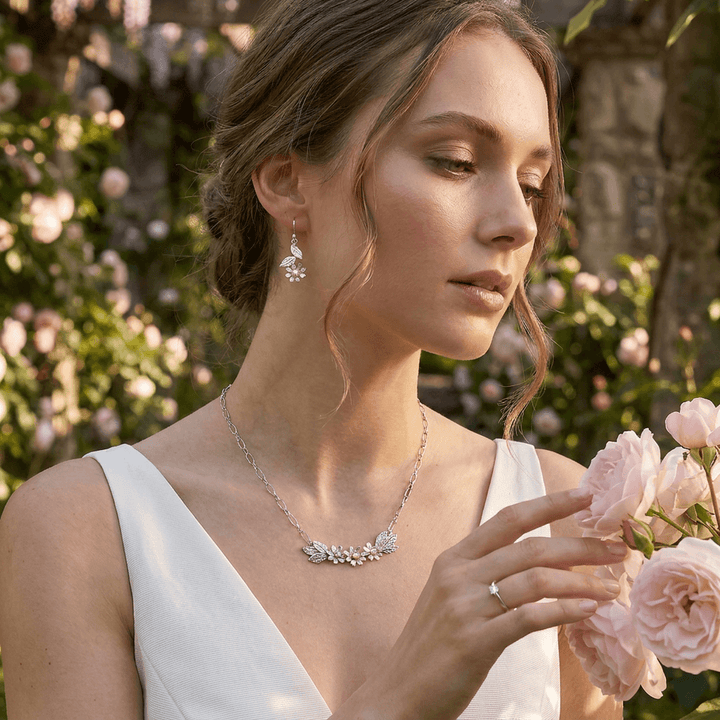 Bride wearing white wildflowers crescent necklace in sterling silver with pearls with matching white wildflower dangle earrings in sterling silver set with pearls
