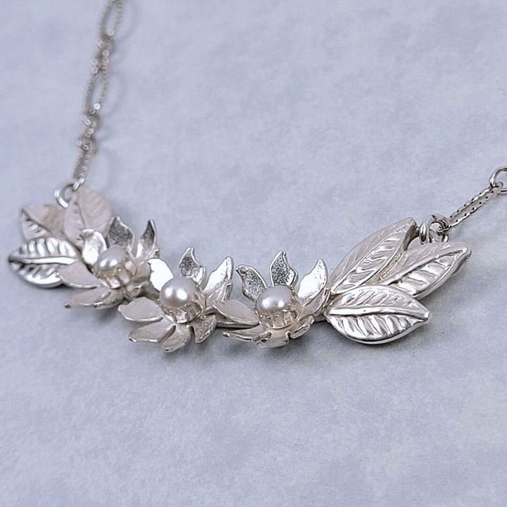 Handmade sterling silver wildflower crescent necklace set with cultured freshwater pearls close-up detail